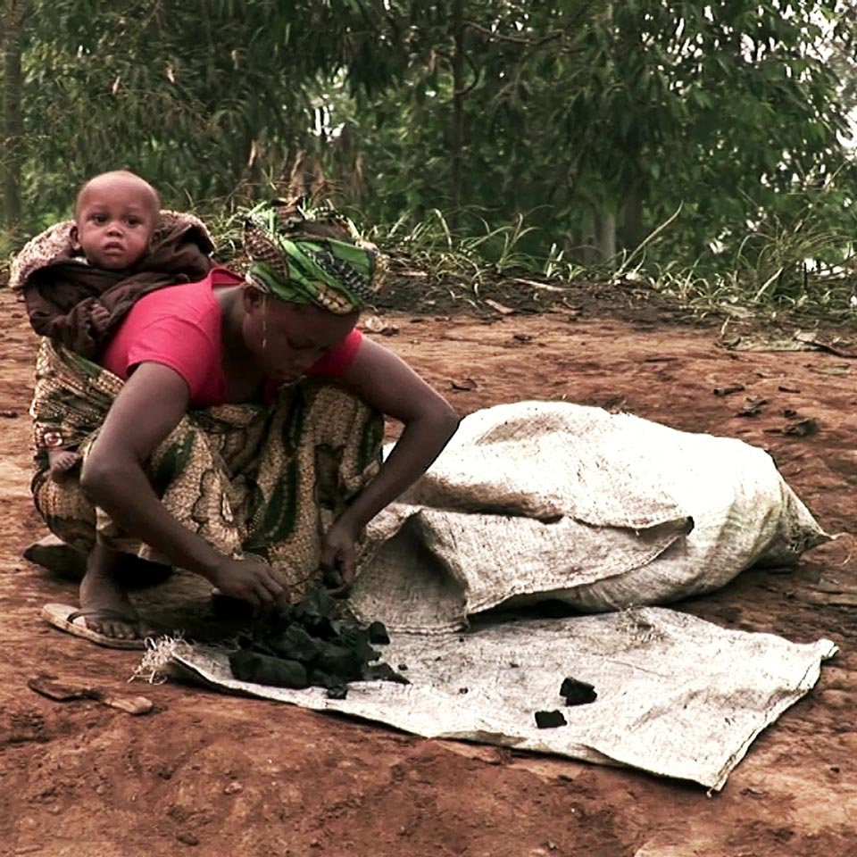 mujer limpiando coltan con niño a cuesta - foto